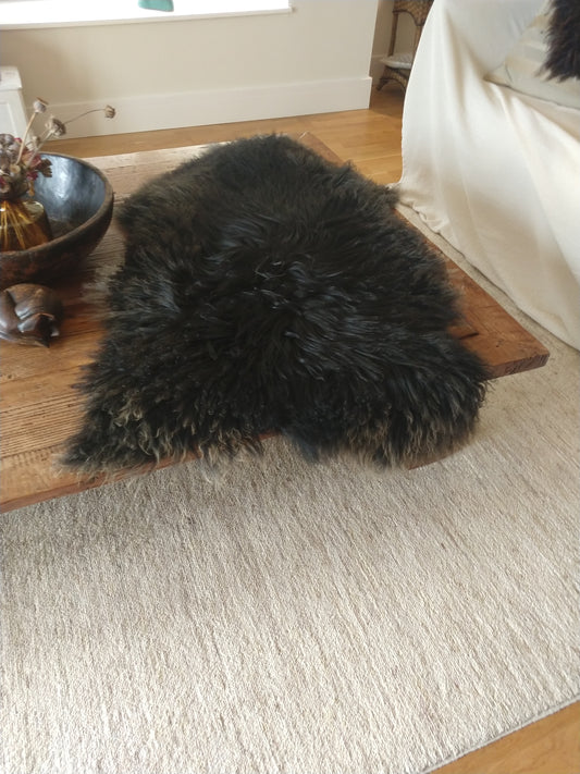 Black Curly sheepskin on a wooden table